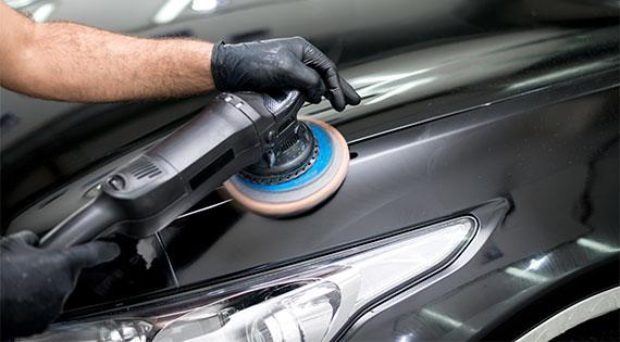 Polijstmachine op de zwarte lak van een wagen